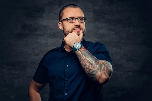 Retrato de hombre barbudo con gafas de sol con tatuaje en el brazo.