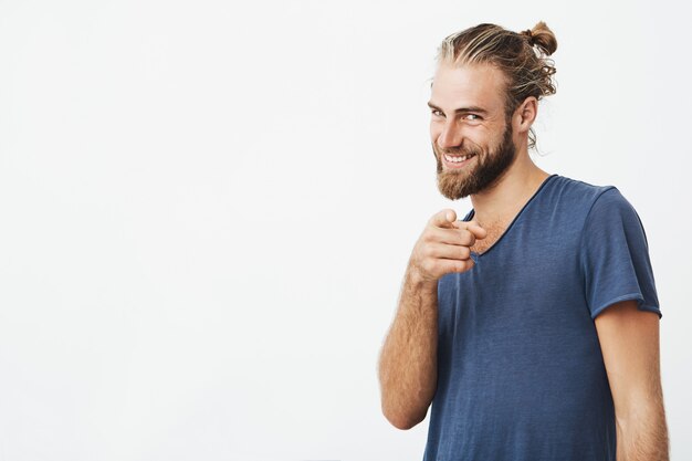 Retrato de hombre barbudo guapo con gran peinado apuntando con el dedo índice