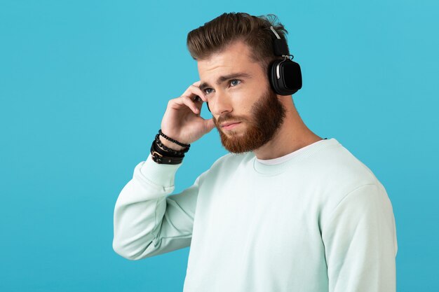 Retrato de hombre barbudo joven atractivo elegante escuchando música en auriculares inalámbricos estilo moderno estado de ánimo seguro