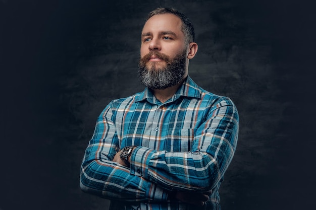 Foto gratuita retrato de un hombre barbudo de mediana edad serio vestido con una camisa de franela a cuadros sobre fondo gris.