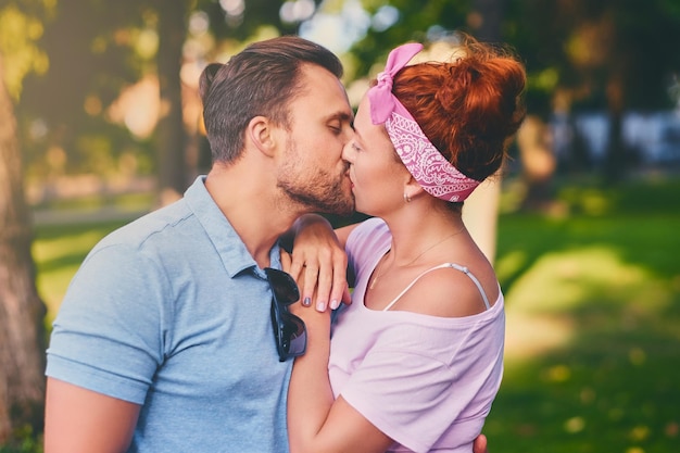 Retrato de hombre barbudo y mujer pelirroja en un parque de la ciudad.