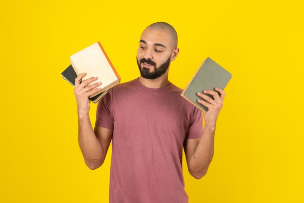 Retrato de un hombre barbudo que muestra la portada del libro sobre la pared amarilla.