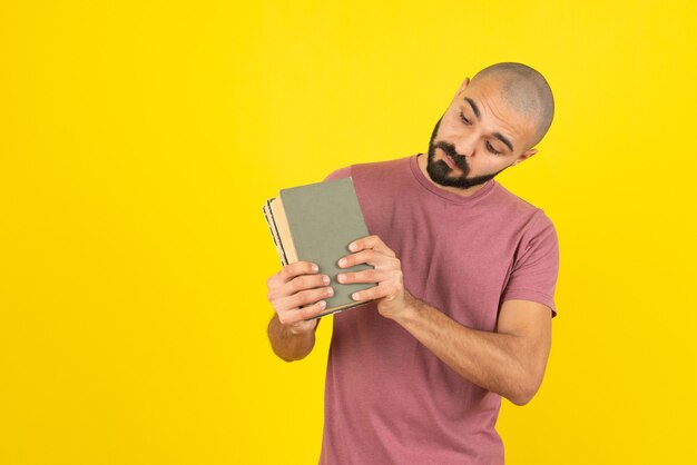 Retrato de un hombre barbudo que muestra la portada del libro sobre la pared amarilla.