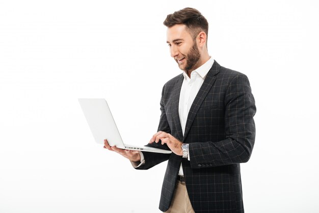 Retrato de un hombre barbudo seguro usando computadora portátil