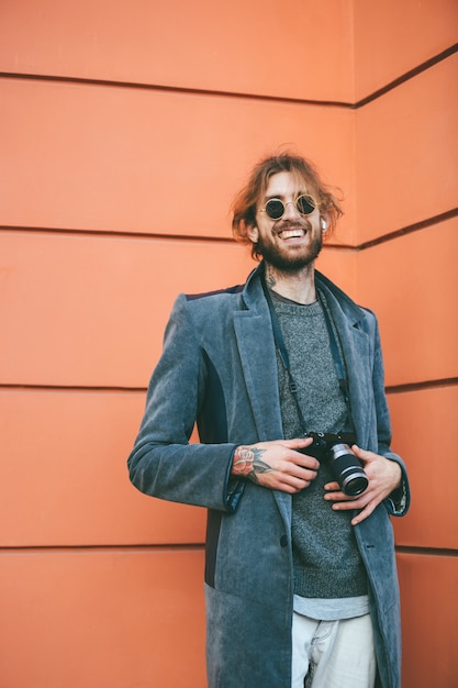 Retrato de un hombre barbudo sonriente con cámara vintage