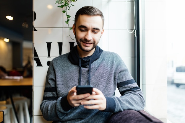 Foto gratuita retrato de hombre barbudo con teléfono móvil en el café