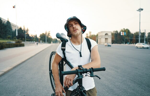 Retrato de un hombre blanco rubio en la ciudad con una bicicleta clásica