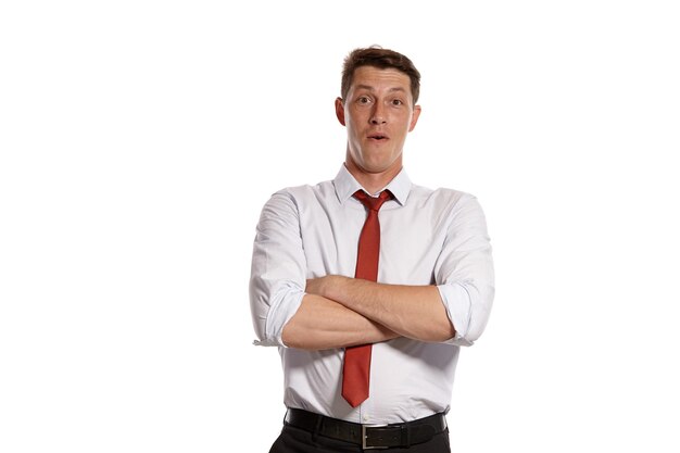 Retrato de un hombre brunet exitoso con ojos marrones, vestido con una camisa blanca y una corbata roja. Cruzó las manos y posó en un estudio aislado sobre un fondo blanco. Concepto de gesticulación y