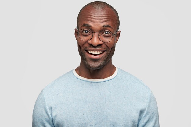 Retrato de hombre calvo joven alegre guapo con expresión alegre, muestra dientes blancos incluso perfectos