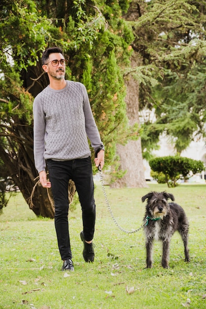 Retrato de hombre caminando con su perro en la hierba verde en el parque