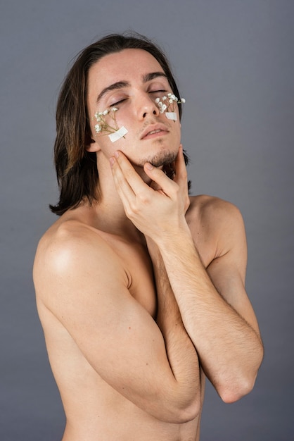 Retrato de hombre sin camisa con flores en el rostro