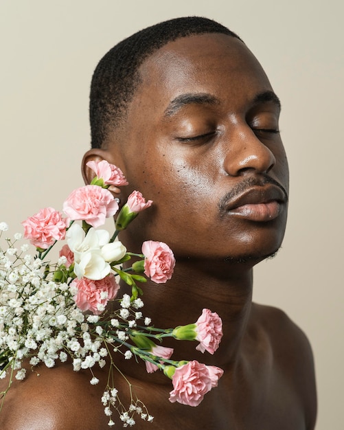 Retrato de hombre sin camisa posando con ramo de flores