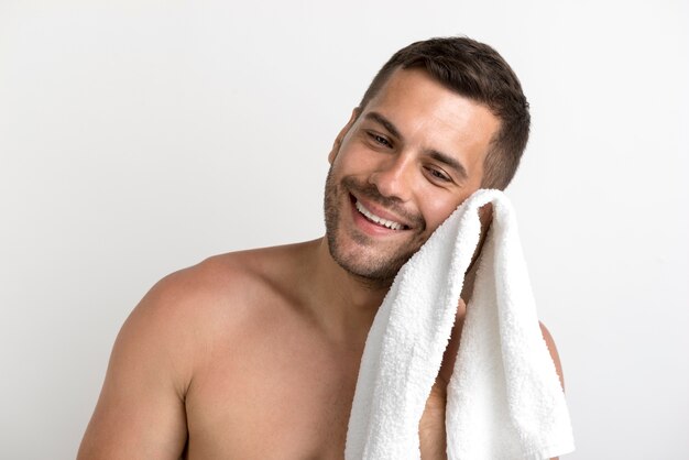 Retrato de hombre sin camisa sonriente limpiándose la cara con una toalla blanca