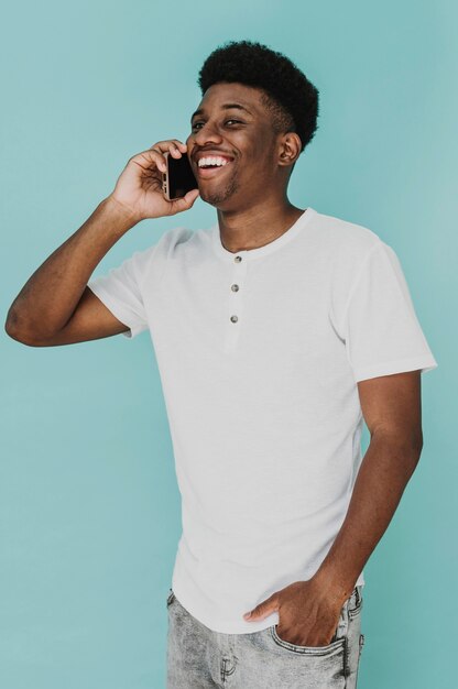 Retrato de hombre en camiseta sonriendo mientras habla por teléfono inteligente