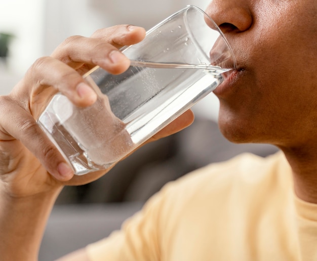 Retrato de hombre en casa bebiendo un vaso de agua