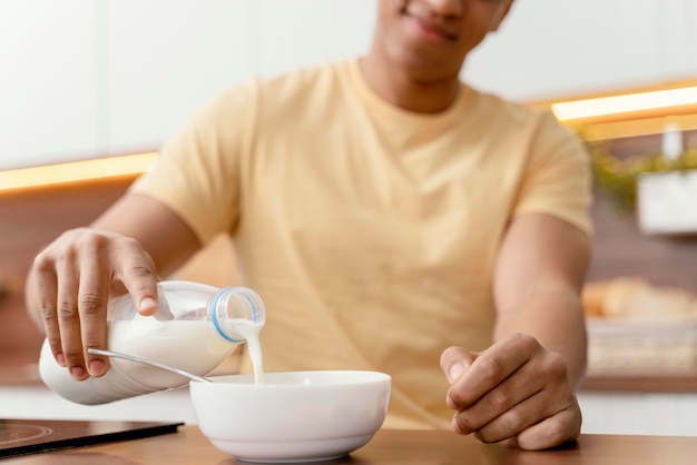 Foto gratuita retrato de hombre en casa vertiendo leche en un tazón