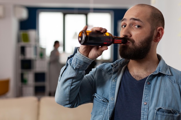 Retrato de un hombre caucásico con una botella de cerveza en una reunión de bebidas después del trabajo con compañeros de trabajo. Persona divirtiéndose con amigos en la oficina de negocios, disfrutando de la celebración de fiestas con comida y alcohol.