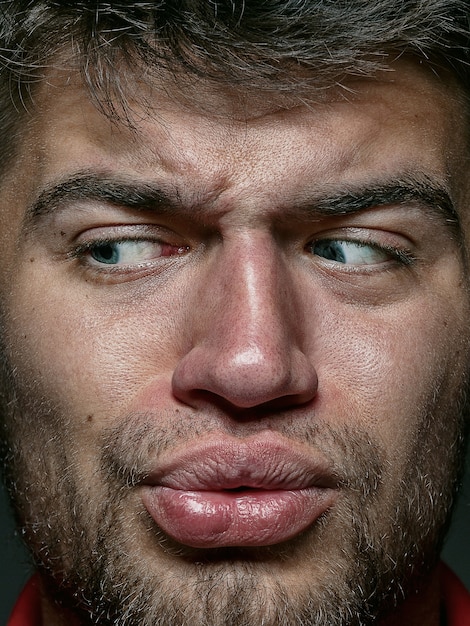 Retrato de hombre caucásico joven y emocional de cerca. modelo masculino con piel cuidada y expresión facial brillante. Concepto de emociones humanas. Sensación repugnante.