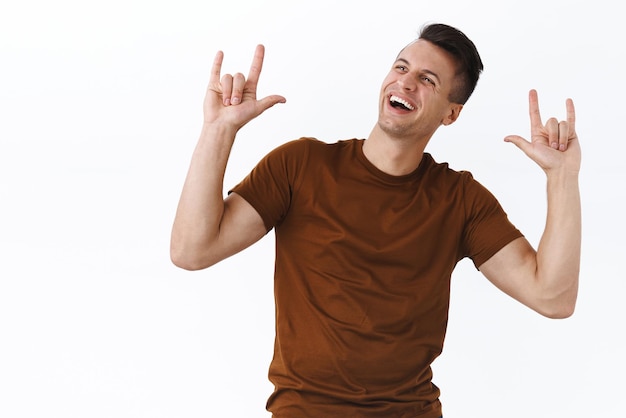 Retrato de un hombre caucásico masculino carismático feliz bailando y disfrutando de la música increíble del sistema de sonido asistir a un festival genial hacer un gesto de rock sonriendo y mirando hacia arriba satisfecho diviértete