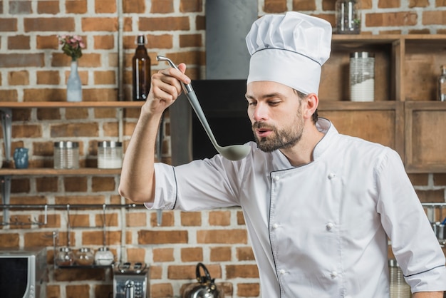 Foto gratuita retrato de hombre chef degustación de sopa en cucharón