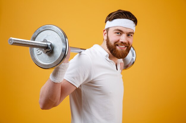 Retrato de un hombre deportivo sonriente haciendo ejercicios con barra