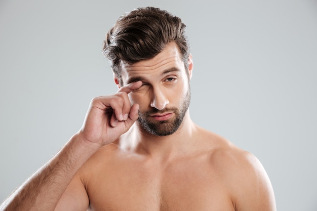 Retrato de un hombre dormido desnudo rascándose el ojo