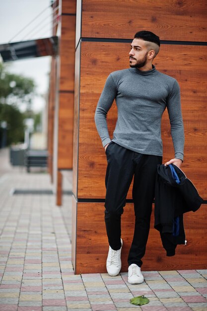 Retrato de un hombre elegante con barba árabe que usa un cuello alto gris y un tipo modelo árabe jaket negro