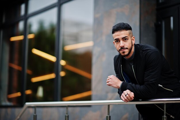 Retrato de un hombre elegante con barba árabe que usa un cuello alto gris y un tipo modelo árabe jaket negro