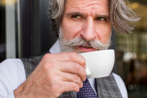 Retrato de hombre elegante disfrutando de la taza de café