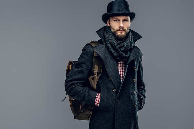 Retrato de un hombre elegante vestido con una chaqueta gris y un sombrero cilíndrico aislado de fondo gris.