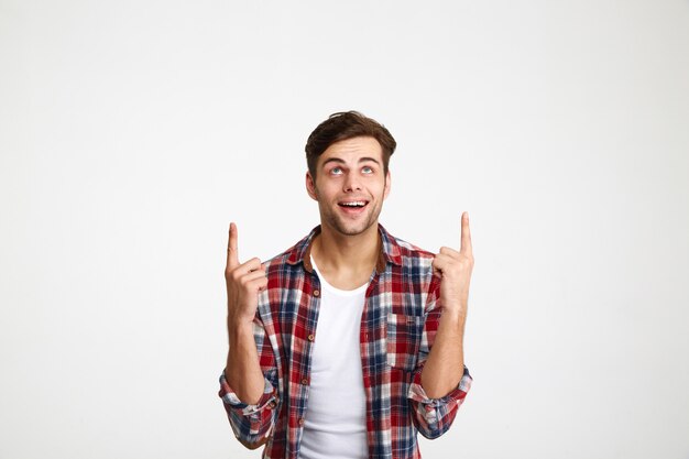 Retrato de un hombre emocionado feliz apuntando con dos dedos