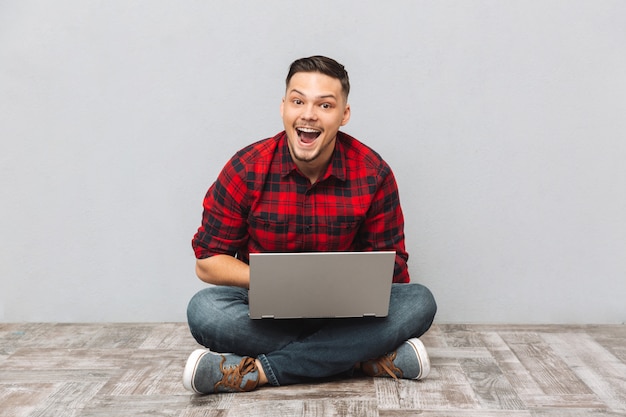 Retrato de un hombre emocionado feliz en camisa a cuadros trabajando