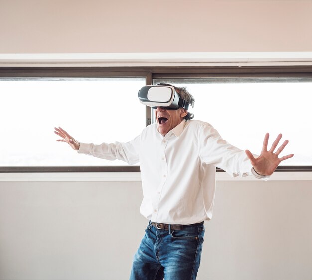 Retrato de hombre emocionado senior experimentando realidad virtual