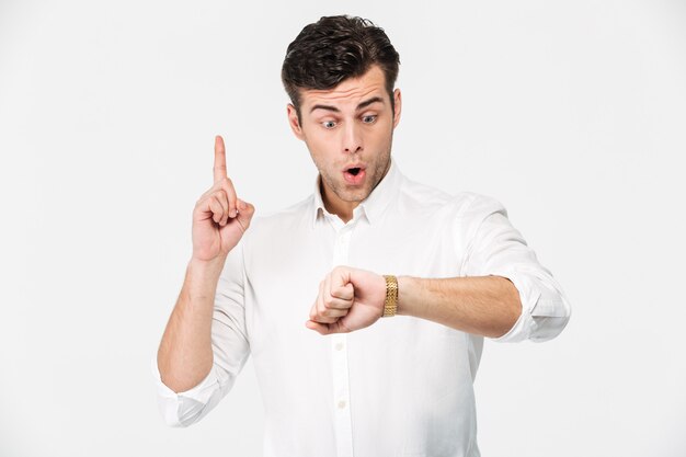 Retrato de un hombre emocionado sorprendido mirando su reloj de pulsera