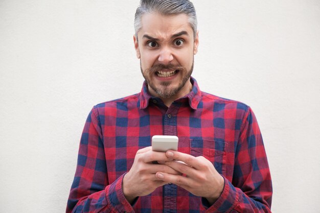 Retrato de hombre enojado con teléfono móvil