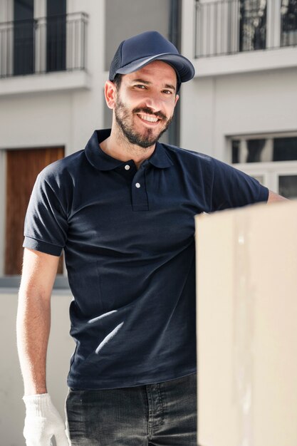 Retrato de un hombre de entrega feliz con caja de cartón