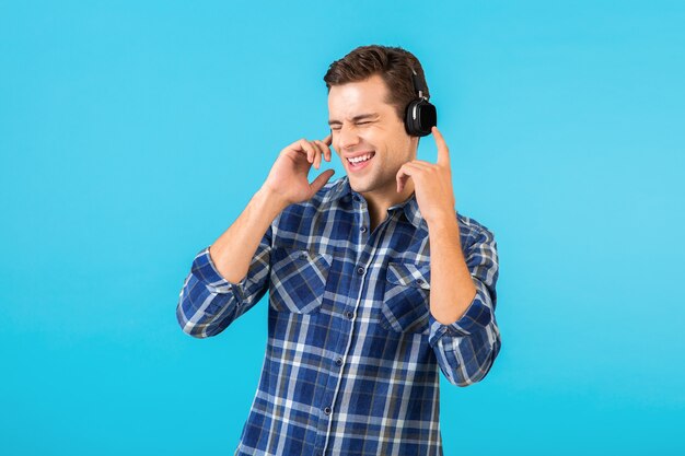 Retrato de hombre escuchando música con auriculares inalámbricos divirtiéndose en azul