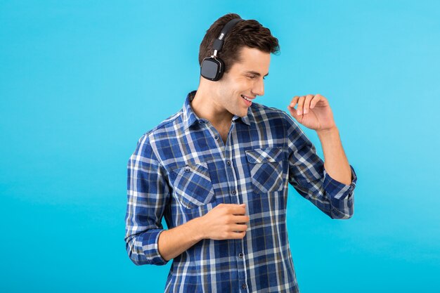 Retrato de hombre escuchando música con auriculares inalámbricos divirtiéndose en azul