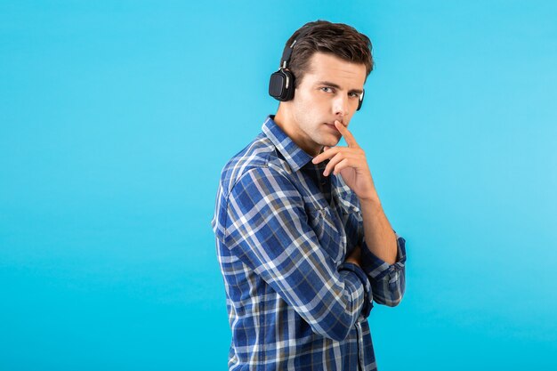 Retrato de hombre escuchando música con auriculares inalámbricos divirtiéndose en azul