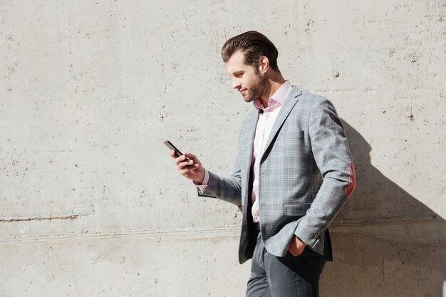 Retrato de un hombre feliz en chaqueta con teléfono móvil