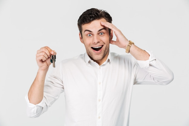 Retrato de un hombre feliz emocionado que sostiene las llaves