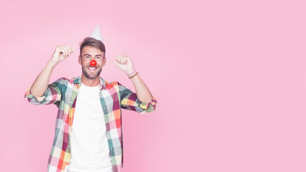 Retrato de un hombre feliz con nariz de payaso sobre fondo rosa