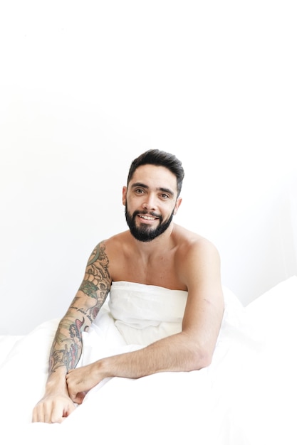 Foto gratuita retrato de un hombre feliz sentado en la cama