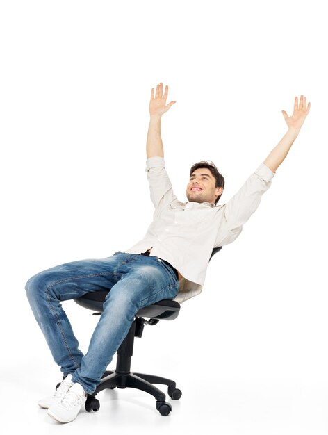 Retrato de hombre feliz sonriente se sienta en la silla y levantó las manos aisladas en blanco.