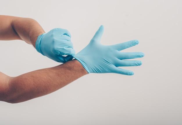 Retrato de un hombre en el fondo blanco con guantes médicos