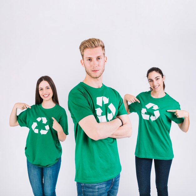 Retrato de un hombre frente a sus amigas mostrando icono de reciclaje en su camiseta verde