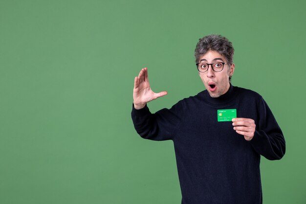 Retrato de hombre genio con tarjeta de crédito en foto de estudio pared verde