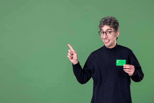 Retrato de hombre genio con tarjeta de crédito verde en foto de estudio pared verde