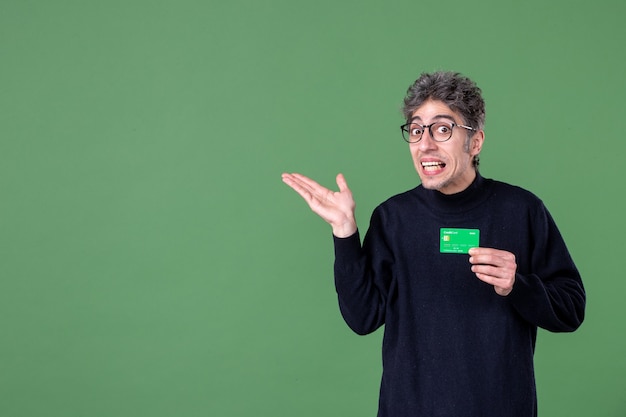 Retrato de hombre genio con tarjeta de crédito verde en foto de estudio pared verde