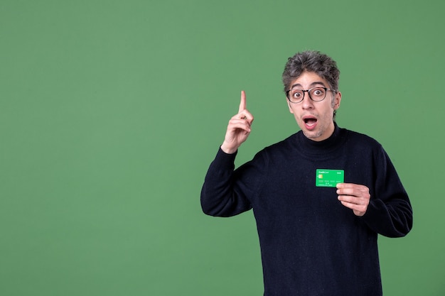 Retrato de hombre genio con tarjeta de crédito verde en foto de estudio pared verde